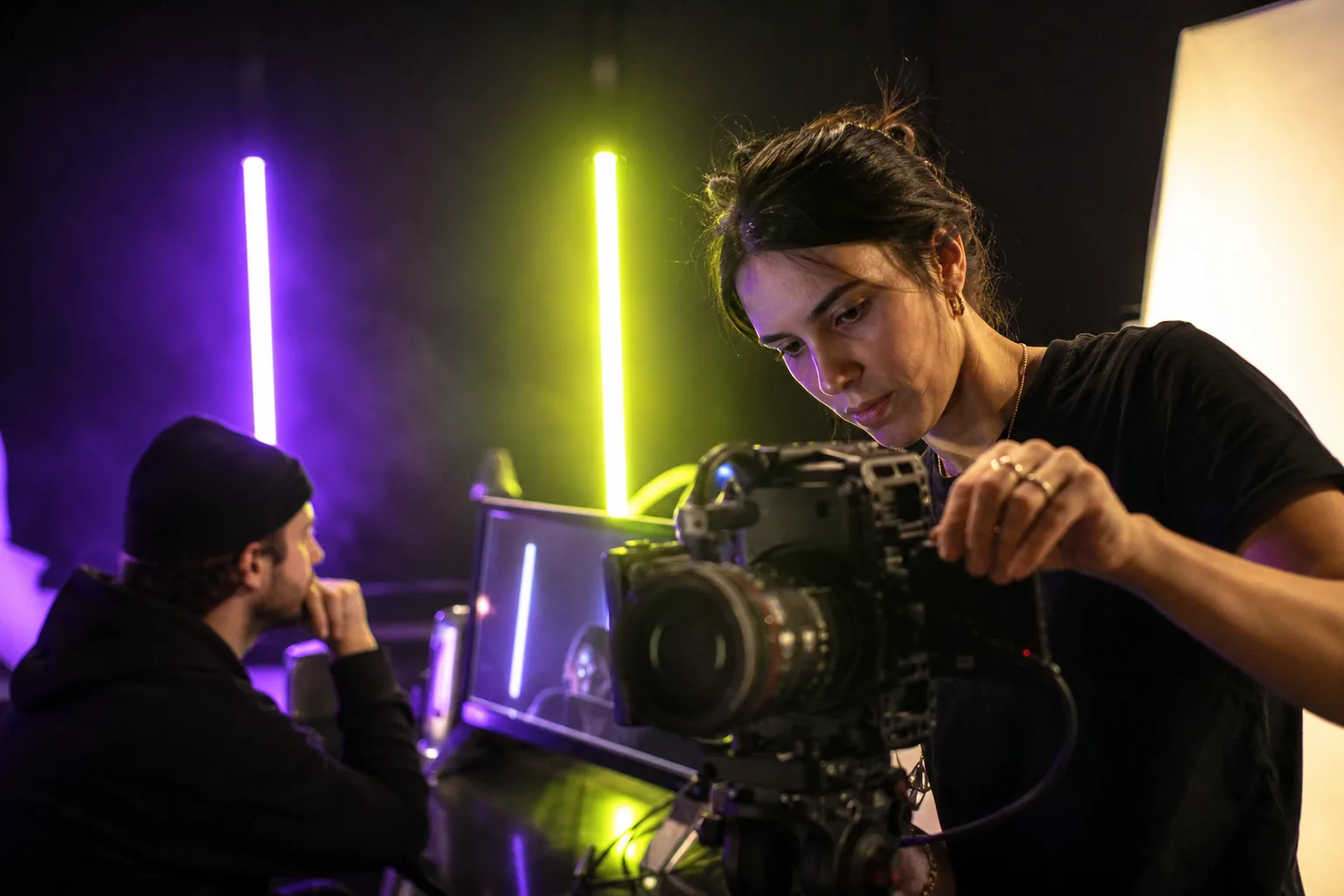 Video creators filming in a studio lit with violet and lime lights.