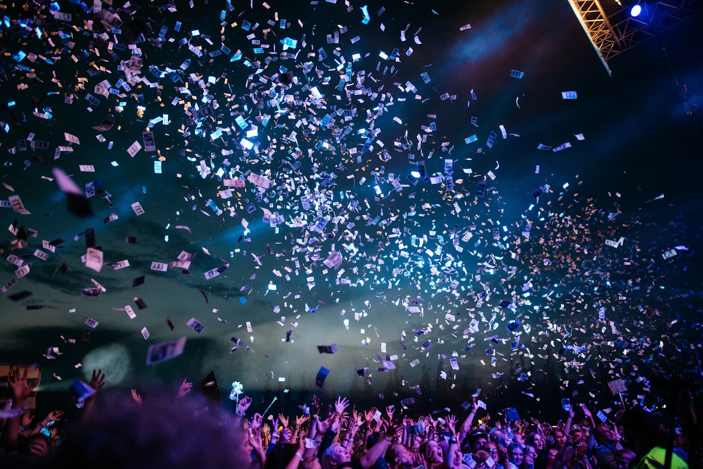 Crowd at a vivid live performance with hands raised in the air.